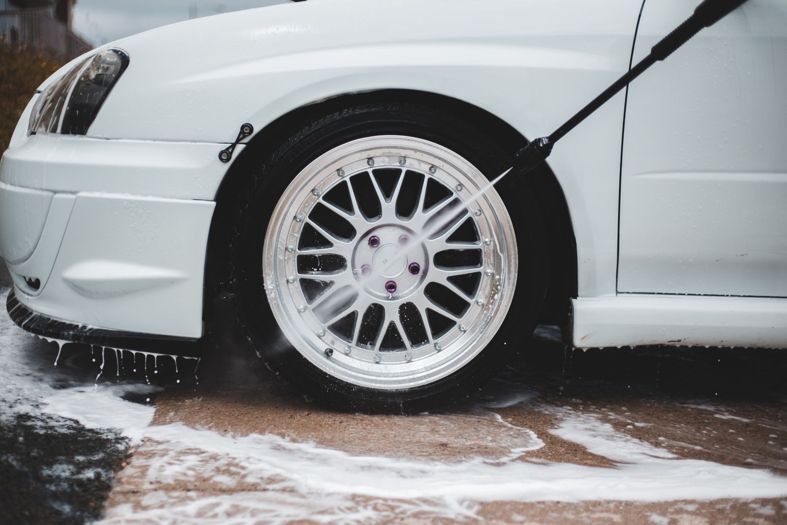 A car wheel being cleaned with water and foam